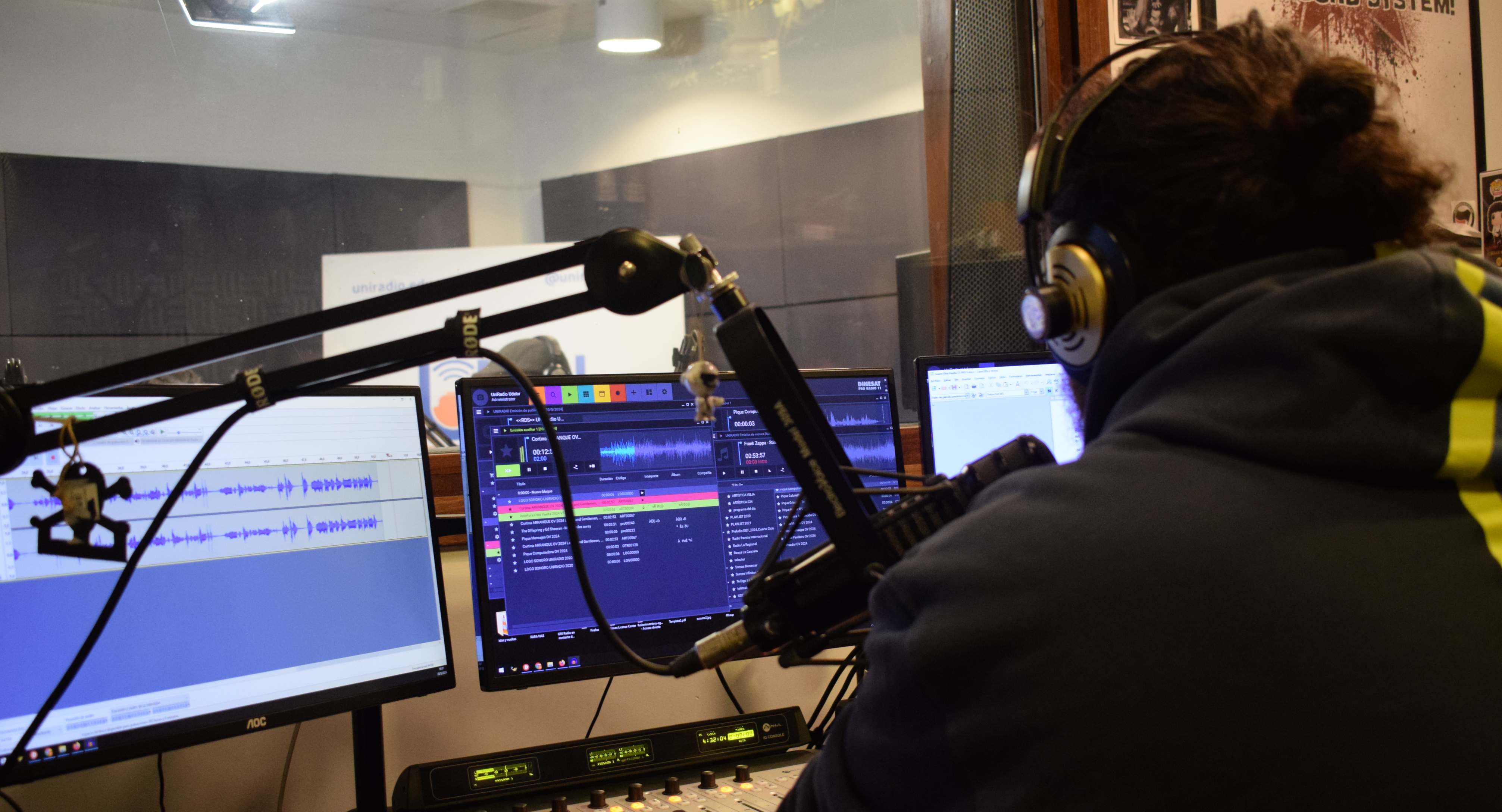 Foto. El operador de la radio en la cabina de operaciones, de espaldas, en plano medio, viste buzo negro y tiene auriculares. 