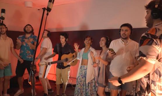 Foto: en un estudio de grabación, cantando, Camilo Estévez con su guitarra y coreutas. 