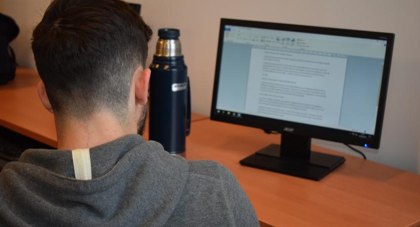 Estudiante de espaldas frente a una computadora