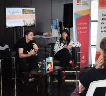 Foto de Romina Verrua y Federico Pritsch durante la presentación del libro de la UDEA. están sentados en sillones negros, Pritsch habla al auditorio. 