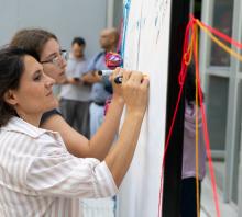 Foto. Encuentro de Mujeres del ASA. Una mujer, de pelo oscuro y camisa blanca, de perfil, escribe sobre un papelógrafo. 